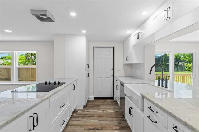 a large white kitchen with a large window and stainless steel appliances