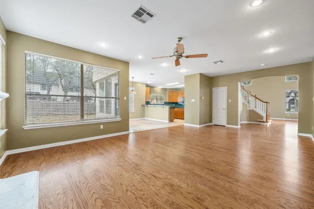a view of an empty room with a window and wooden floor