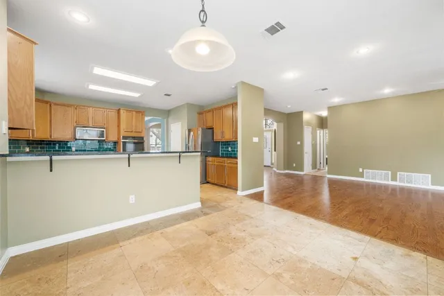 a view of a kitchen with kitchen island a sink stainless steel appliances and cabinets
