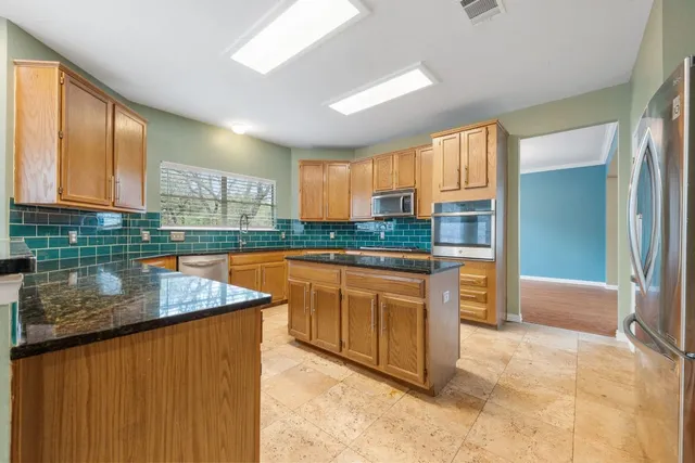 a kitchen with stainless steel appliances granite countertop a stove a sink and a refrigerator