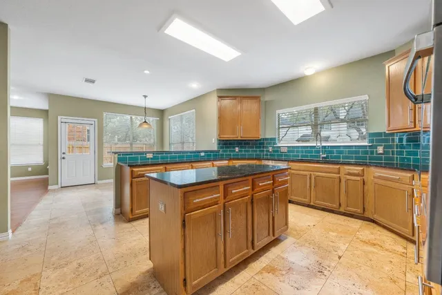 a large kitchen with granite countertop a sink and cabinets