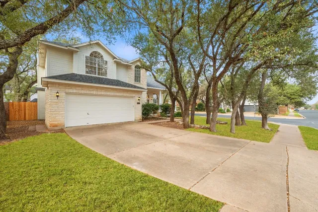 front view of house with a yard and trees