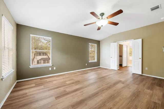 a view of an empty room with window and wooden floor