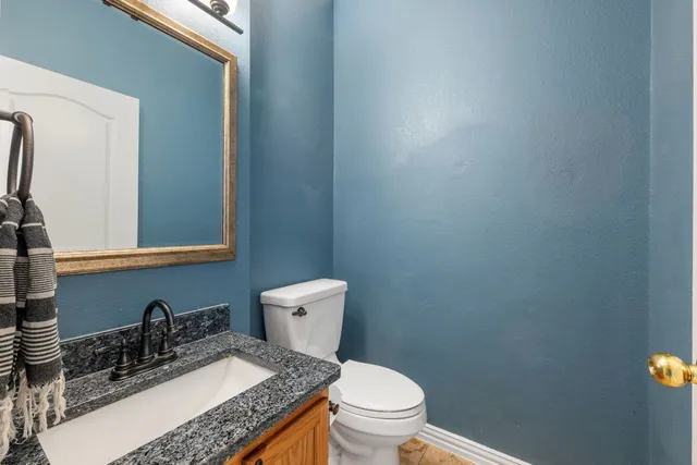 a bathroom with a granite countertop toilet and sink