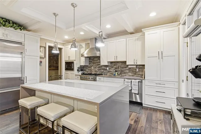 a large white kitchen with a refrigerator a stove a sink and a dining table with wooden floor