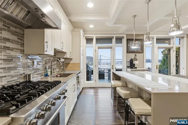 a large kitchen with stainless steel appliances a sink a stove and a wooden floors
