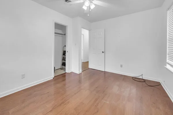 a view of a room with wooden floor and a ceiling fan