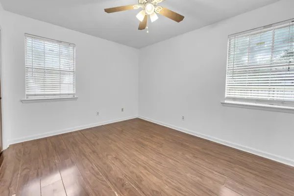 an empty room with wooden floor and windows