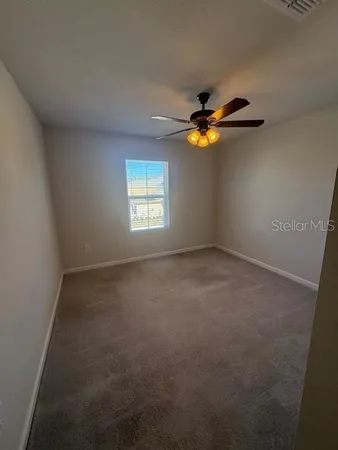 an empty room with windows and chandelier fan