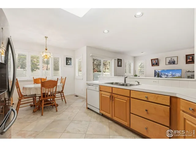 a open kitchen with stainless steel appliances granite countertop a dining table chairs and a refrigerator