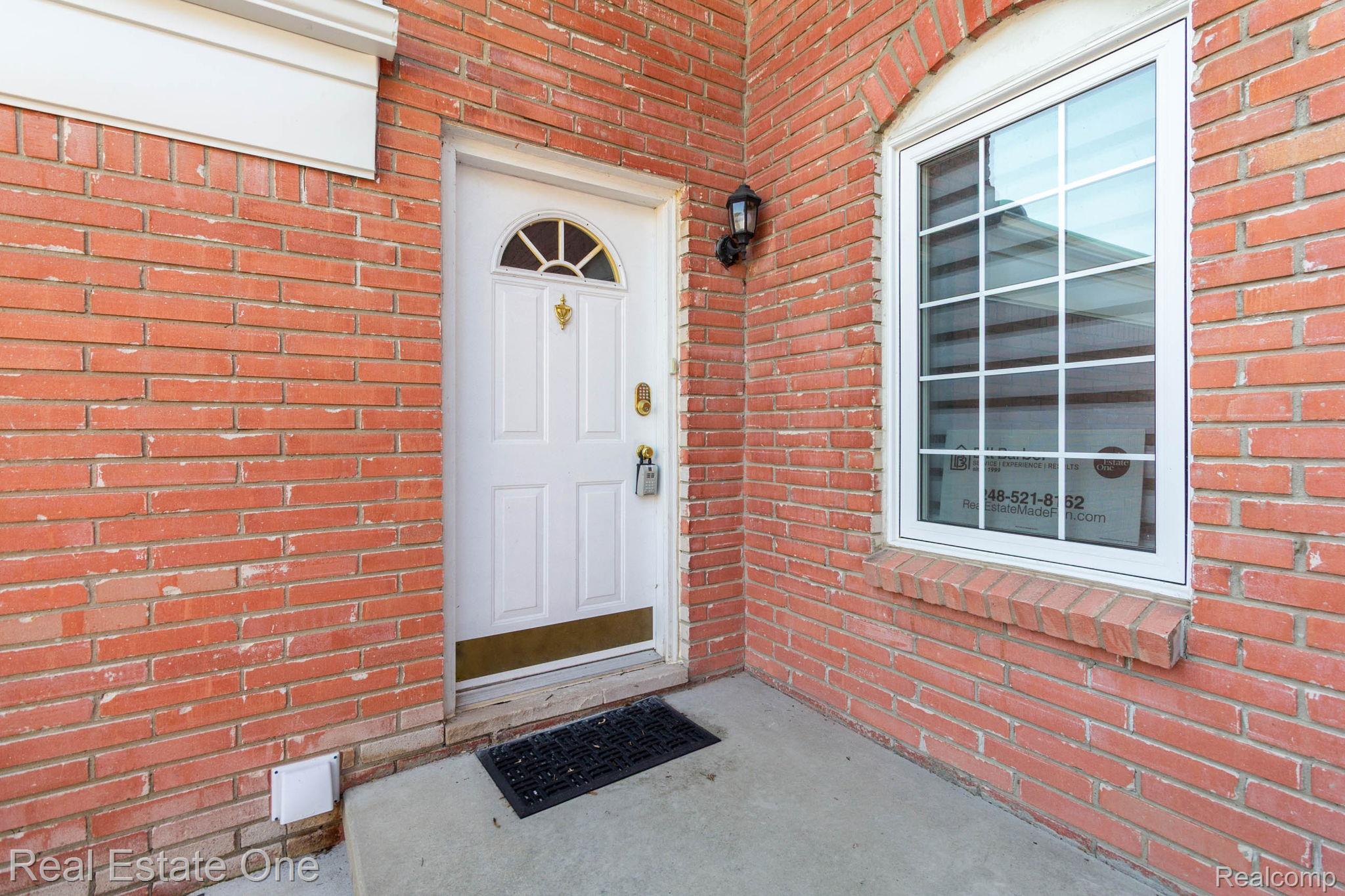 111 Manor Way Rochester, MI 48309 - Photo 4 of 36 Red brick exterior featuring a white paneled entry door with an arched transom