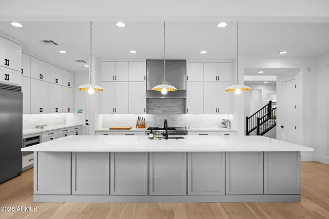 a large kitchen with stainless steel appliances kitchen island granite countertop a sink a stove a refrigerator and a cabinets