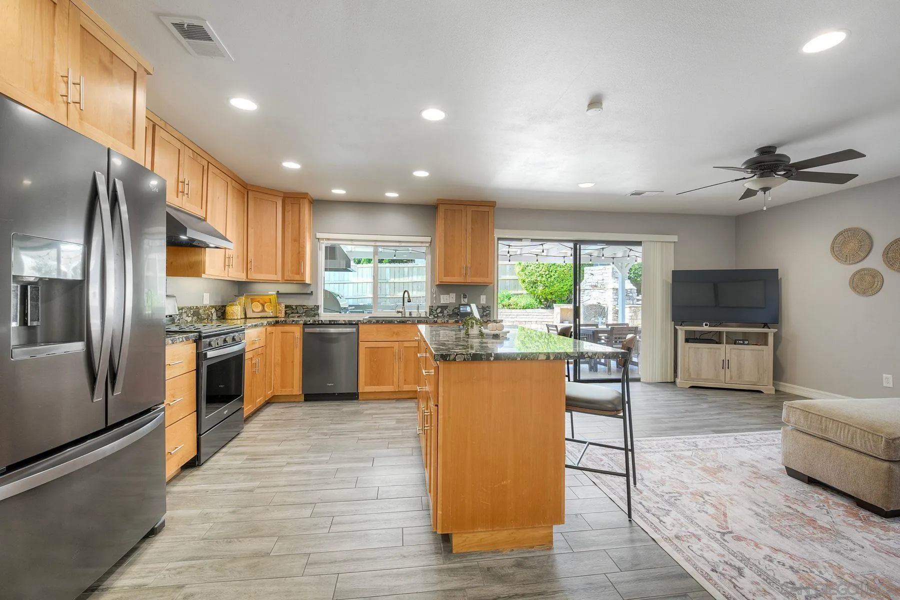 17240 Cuvee Court Poway, CA 92064 - Photo 21 of 62 a kitchen with stainless steel appliances granite countertop a refrigerator a sink dishwasher a stove top oven a kitchen island and couches with wooden floor
