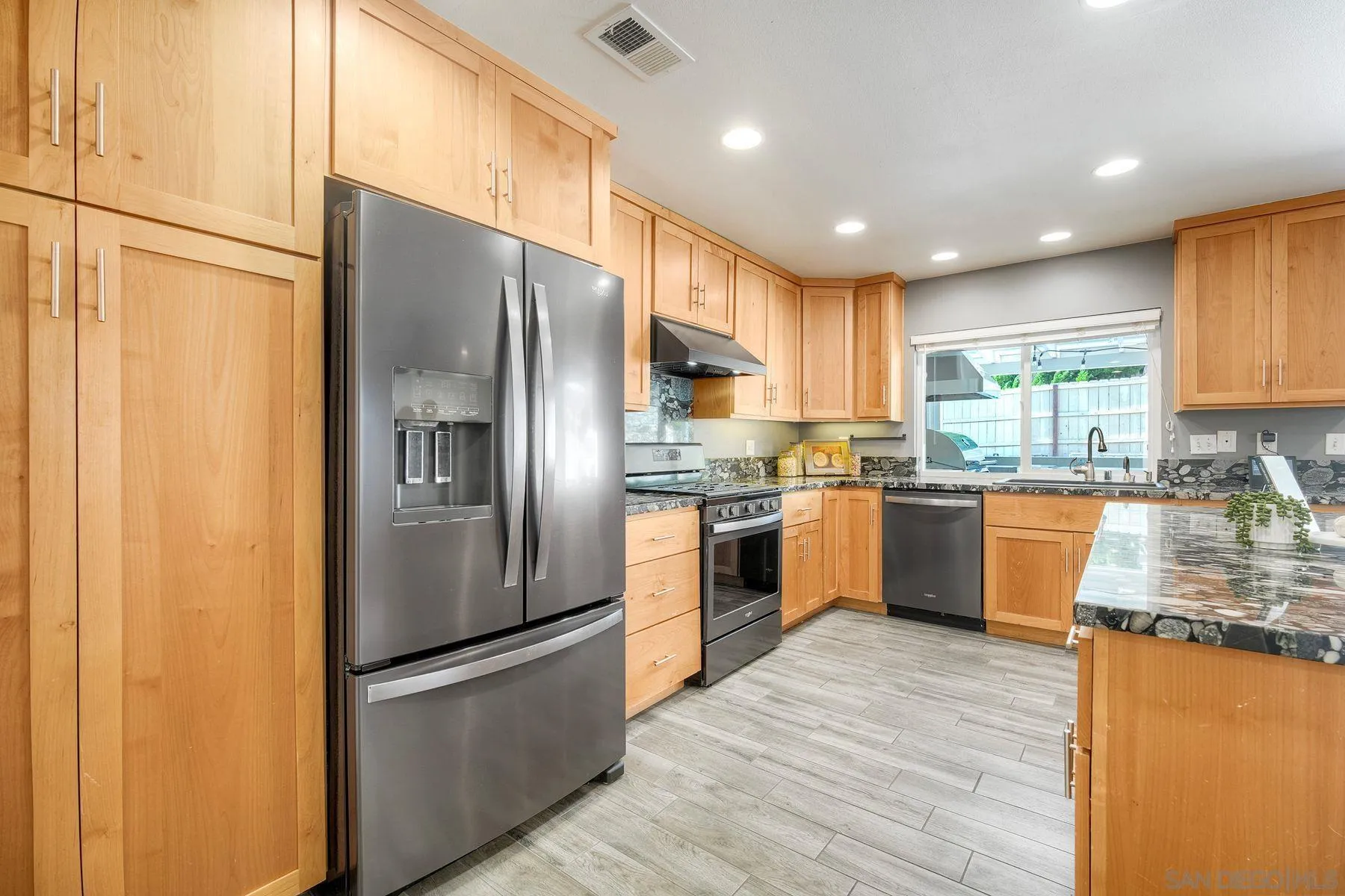 17240 Cuvee Court Poway, CA 92064 - Photo 23 of 62 a kitchen with stainless steel appliances granite countertop a refrigerator a sink dishwasher a stove top oven a kitchen island and couches with wooden floor