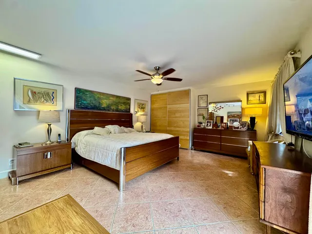 a spacious bedroom with a bed and a flat tv screen on dresser