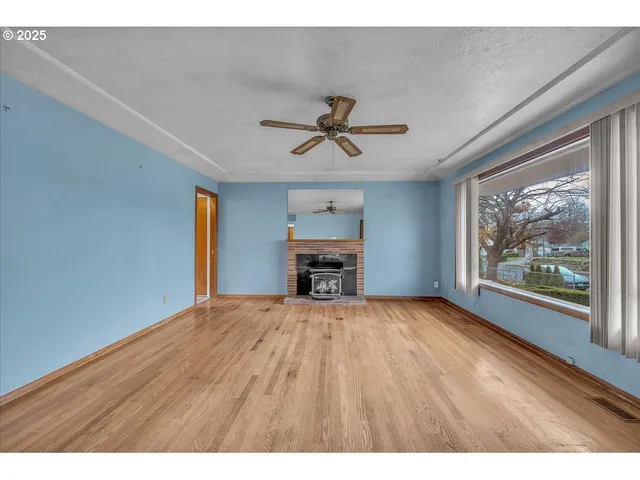 a view of an empty room with a window and a kitchen