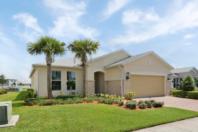 a front view of a house with a garden and trees