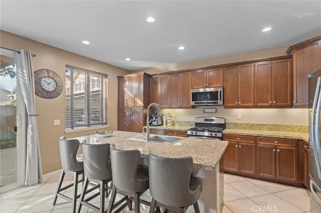 a kitchen with stainless steel appliances granite countertop a stove a sink a microwave a refrigerator and cabinets