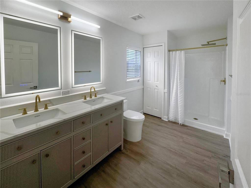 2109 Aitkin Loop Leesburg, FL 34748 - Photo 11 of 33 a spacious bathroom with a double vanity sink double mirror and toilet