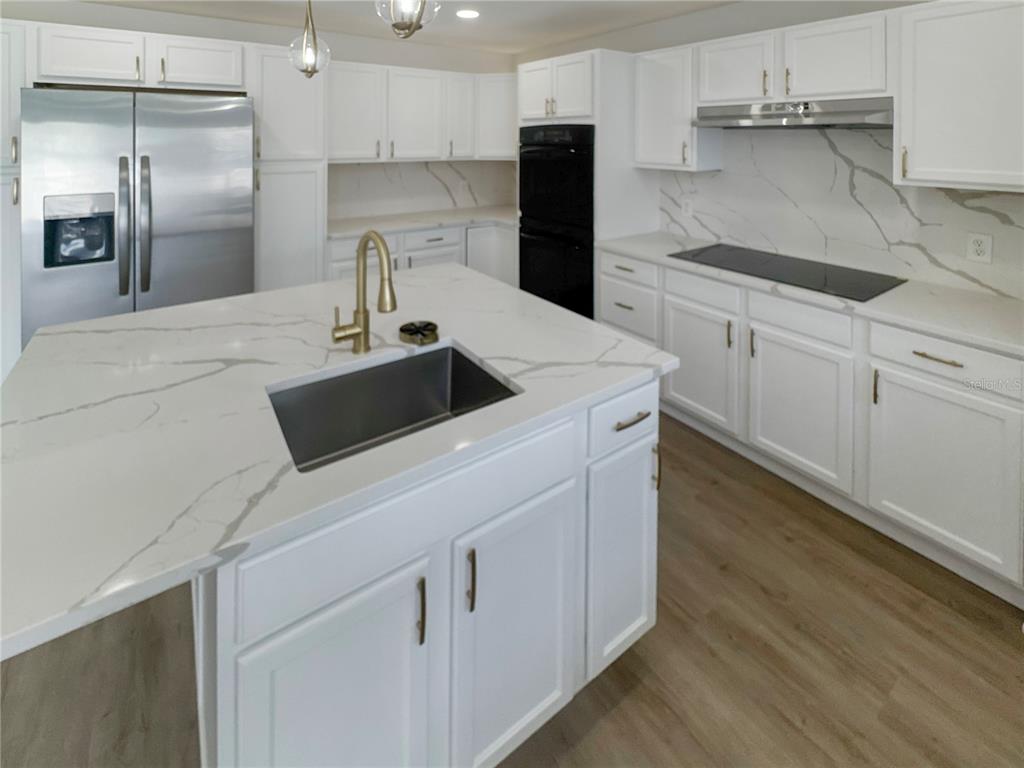 2109 Aitkin Loop Leesburg, FL 34748 - Photo 3 of 33 a kitchen with white cabinets and stainless steel appliances
