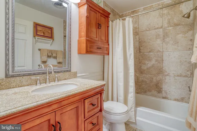 a bathroom with a granite countertop sink a toilet and shower