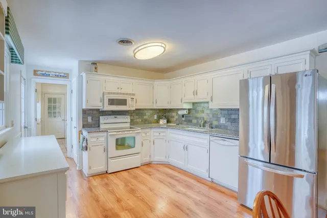a kitchen with stainless steel appliances granite countertop a refrigerator a stove top oven and white cabinets