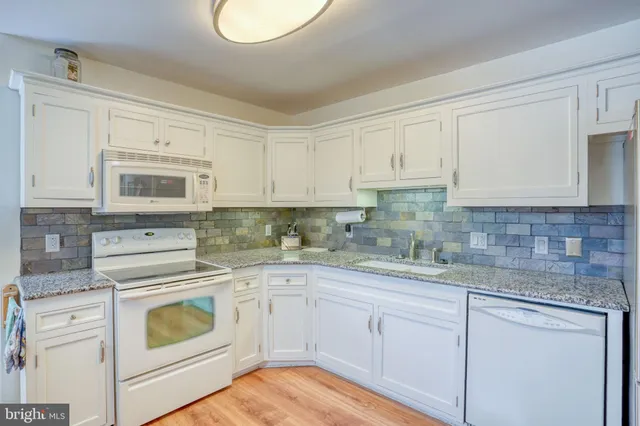 a kitchen with white cabinets white stainless steel appliances and sink