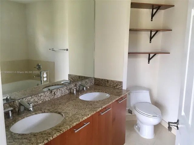a bathroom with a granite countertop sink a toilet and a mirror