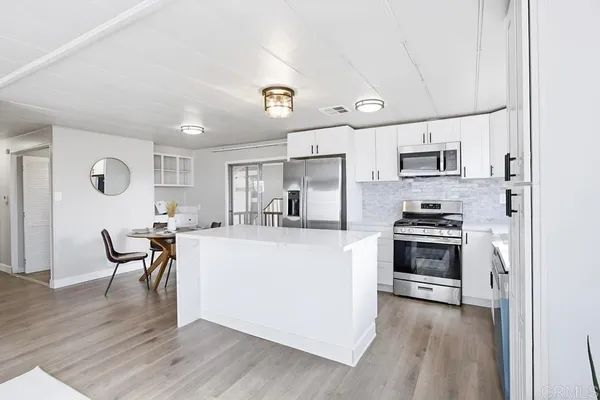 a kitchen with kitchen island a stove a table and chairs in it