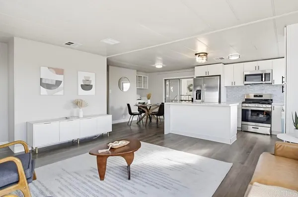 a living room with furniture and kitchen view with wooden floor
