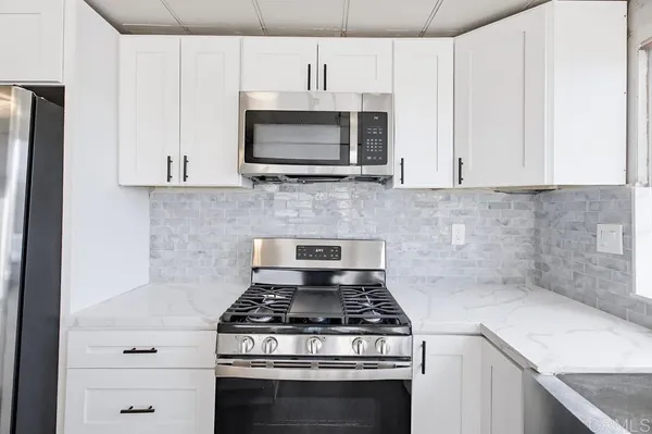 a kitchen with stainless steel appliances granite countertop white cabinets a microwave oven and a sink