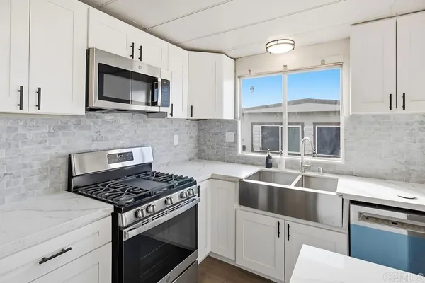 a kitchen with white cabinets and appliances