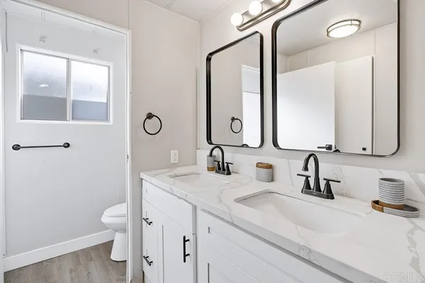 a bathroom with a double vanity sink toilet and mirror