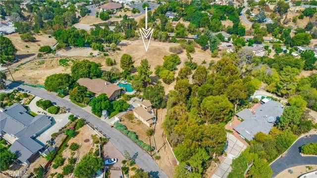 an aerial view of residential houses with outdoor space and trees