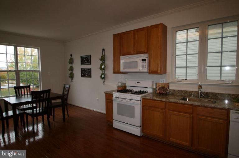 18107 Coachmans Road Germantown, MD 20874 - Photo 2 of 21 a kitchen with stainless steel appliances granite countertop wooden cabinets a stove a sink a dining table and chairs