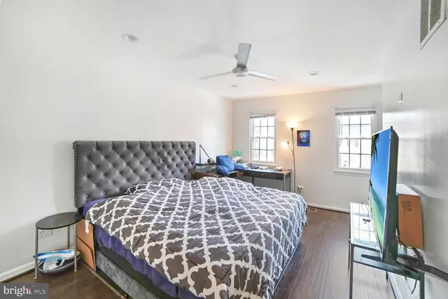 a bedroom with a bed and a dresser with wooden floor