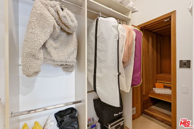 a view of walk in closet with clothes and shoes
