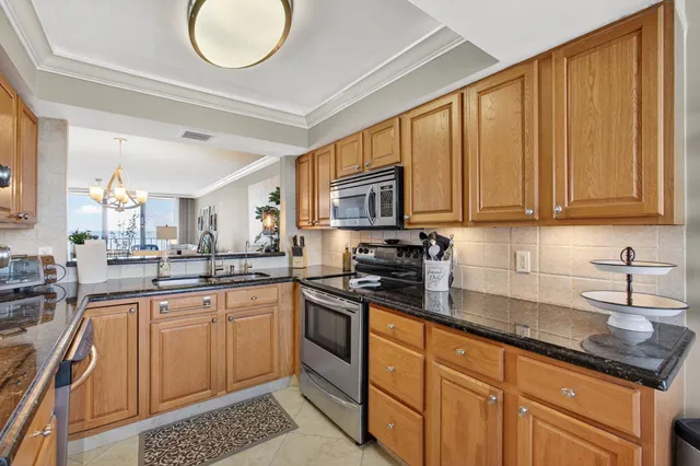 a kitchen with stainless steel appliances granite countertop a sink stove refrigerator granite counter tops and white cabinets with wooden floor