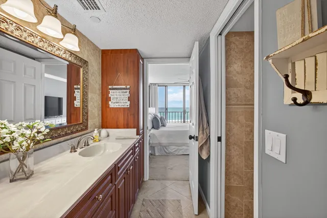 a bathroom with a granite countertop double vanity sink a mirror a vanity and a shower
