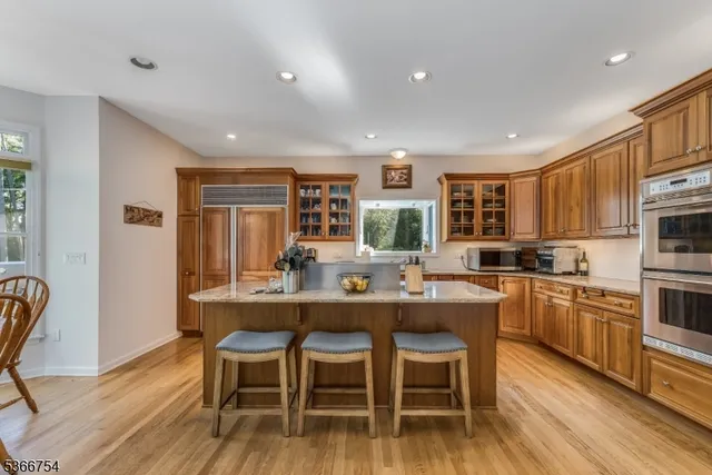 a kitchen with stainless steel appliances granite countertop a dining table chairs stove refrigerator and cabinets