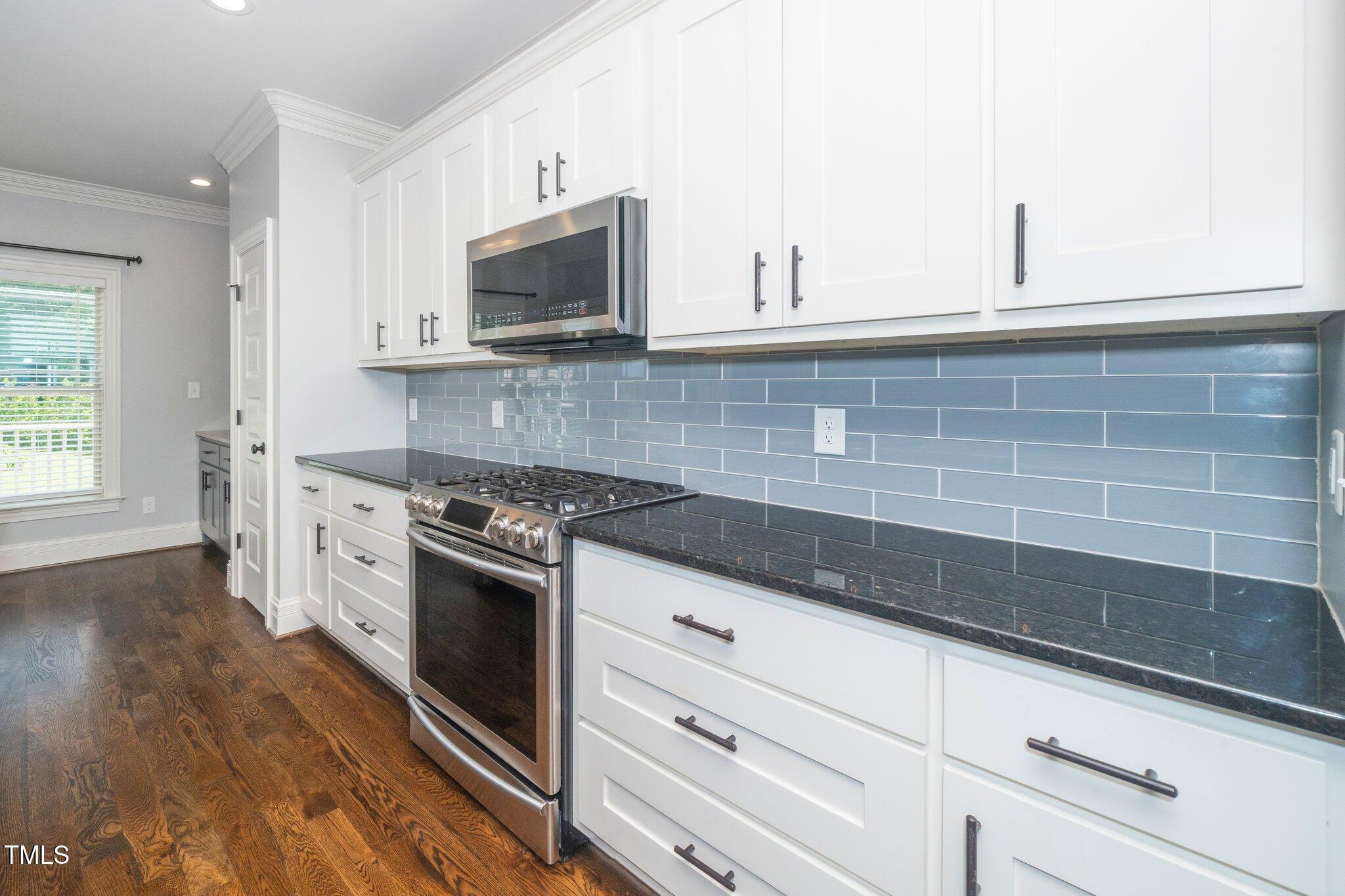 6737 Dwight Rowland Road Willow Spring, NC 27592 - Photo 19 of 50 a kitchen with white cabinets stainless steel appliances and wooden floor