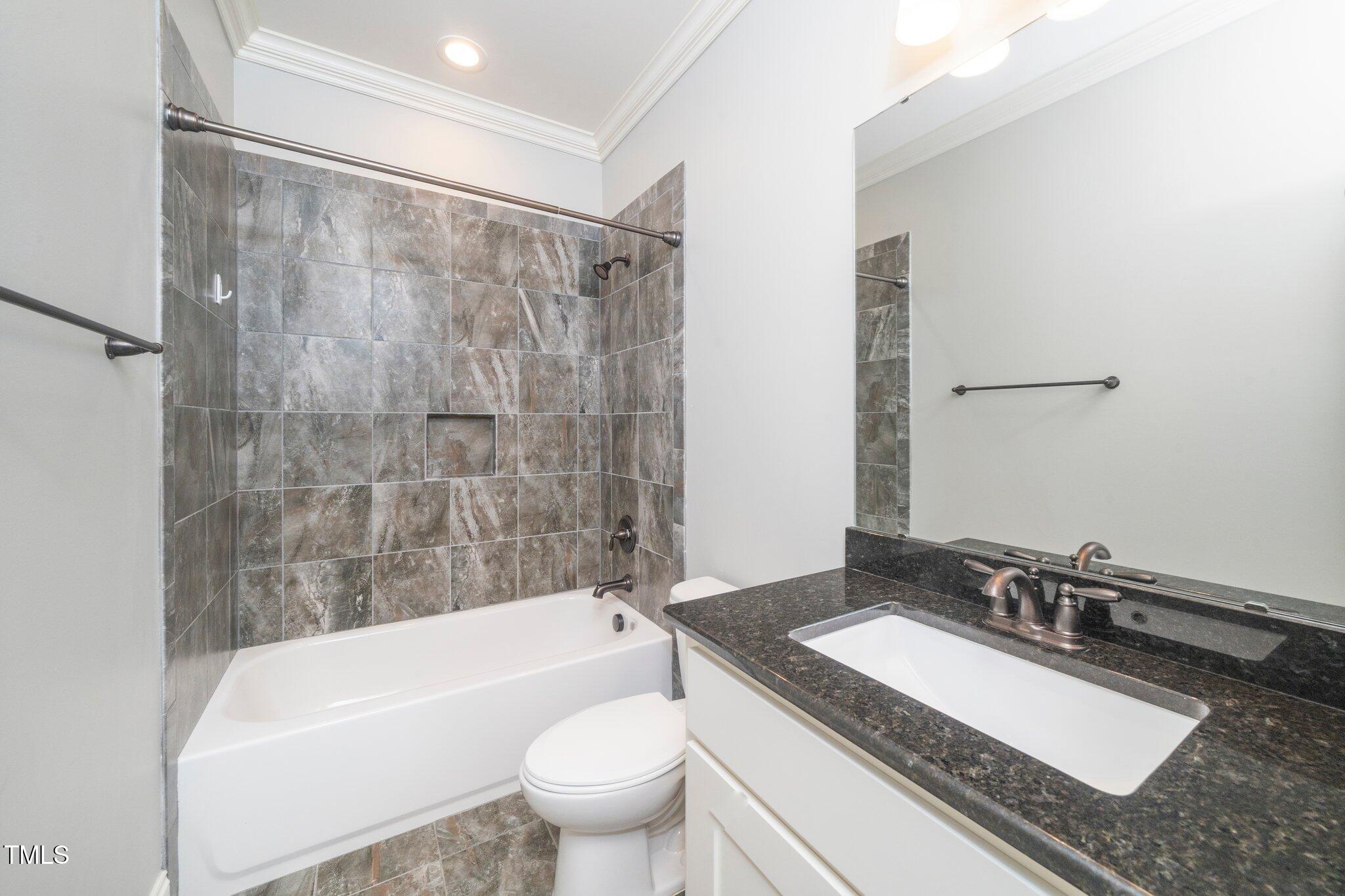 6737 Dwight Rowland Road Willow Spring, NC 27592 - Photo 22 of 50 a bathroom with a granite countertop sink a toilet a mirror a bathtub and shower