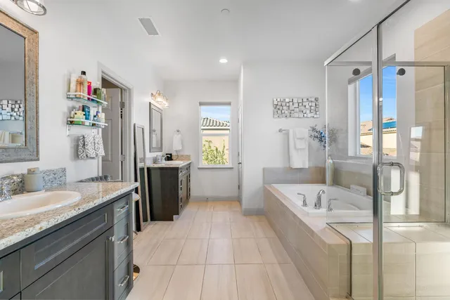 a spacious bathroom with a granite countertop sink a mirror and a bathtub