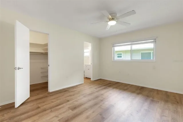 an empty room with wooden floor ceiling fan and windows