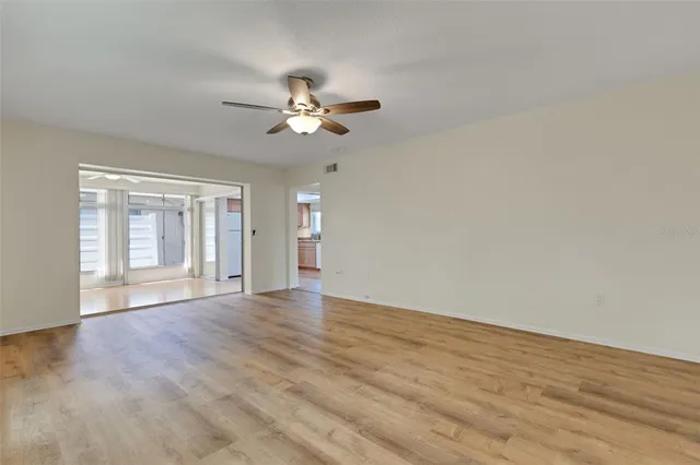 a view of an empty room with a window and wooden floor