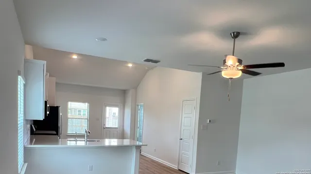 a room with a chandelier fan and kitchen view
