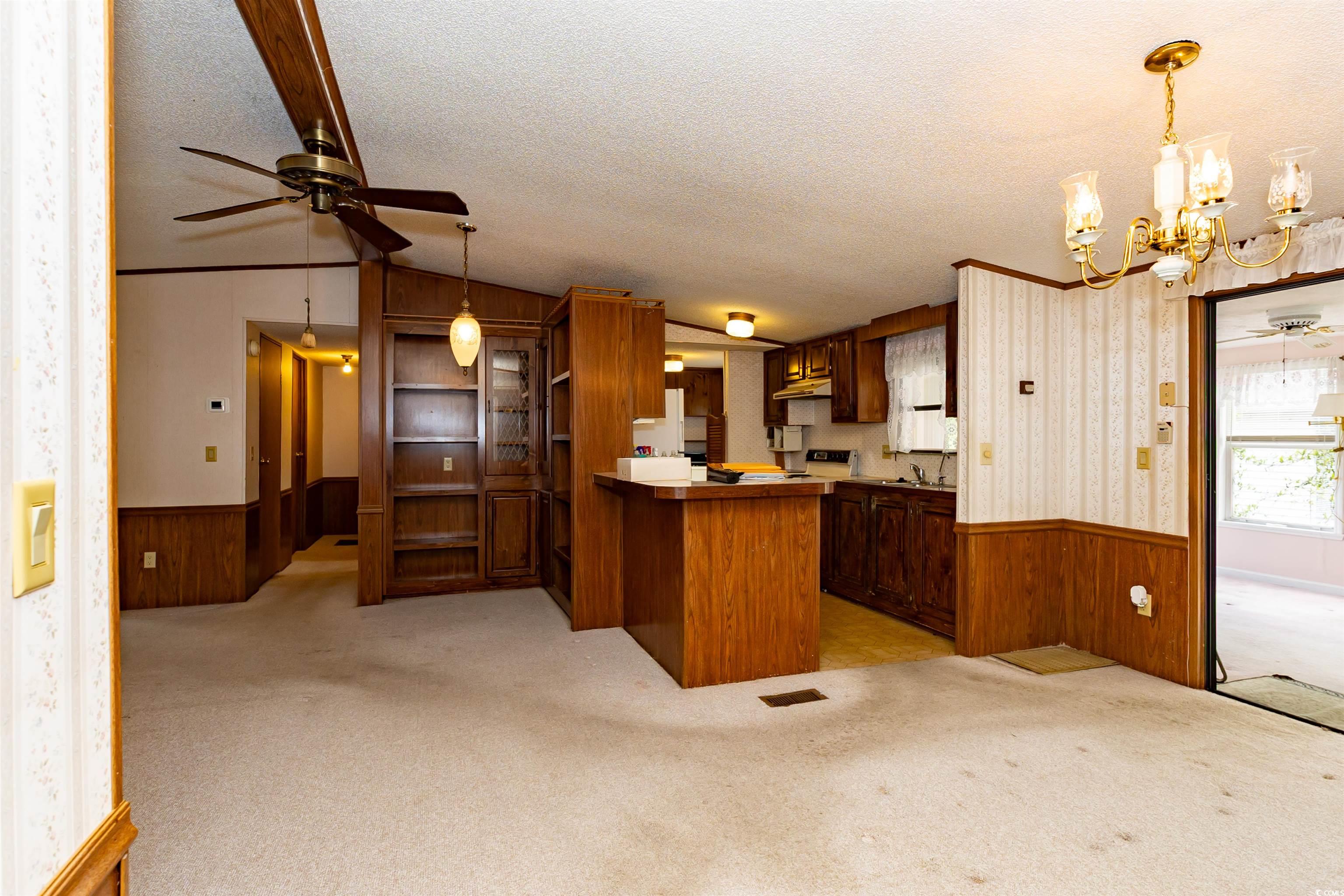 835 South Marlin Circle Murrells Inlet, SC 29576 - Photo 7 of 31 Kitchen with wood walls, a wainscoted wall, and ceiling fan with notable chandelier