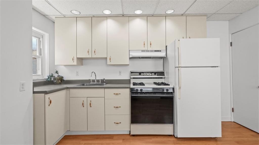 210 19th Street Pittsburgh, PA 15215 - Photo 13 of 33 a kitchen with granite countertop a refrigerator stove a sink and white cabinets with wooden floor