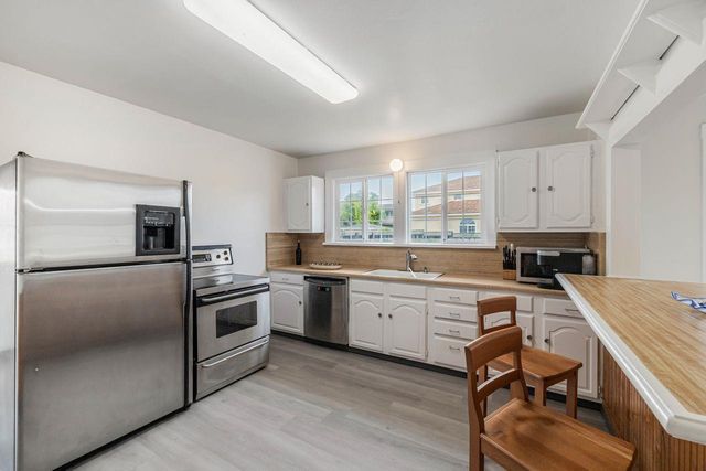 a large kitchen with kitchen island granite countertop lots of white cabinets a sink and dishwasher