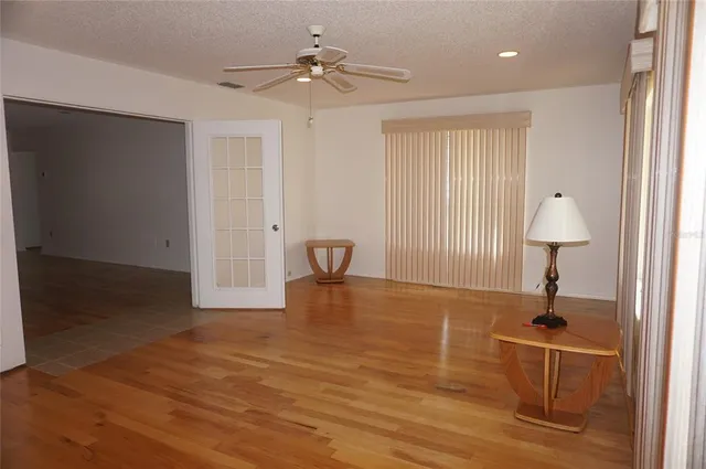 a view of empty room with wooden floor and fan